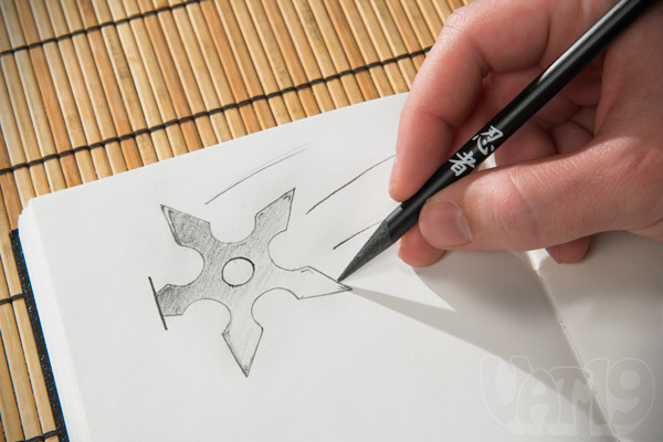 Man using a Ninja Pencil to draw a throwing star.